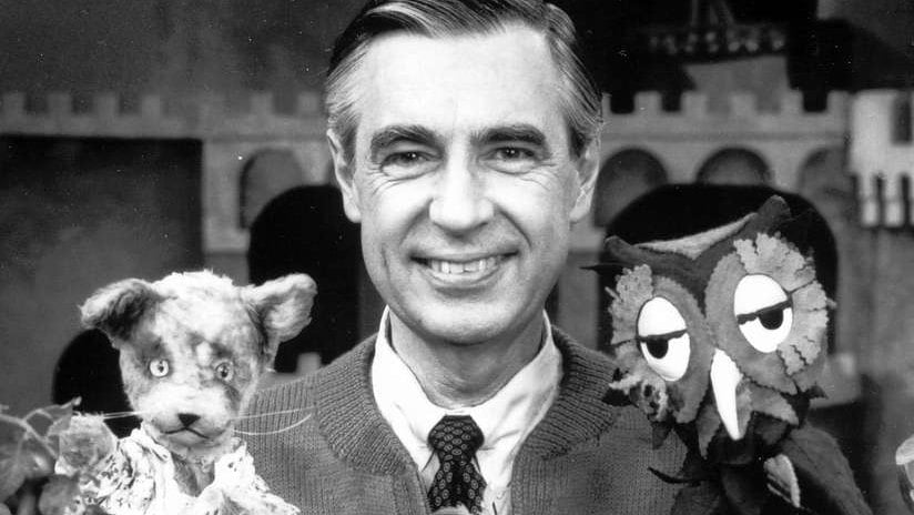 a black and white picture of Mr. Rogers holding two of his puppets